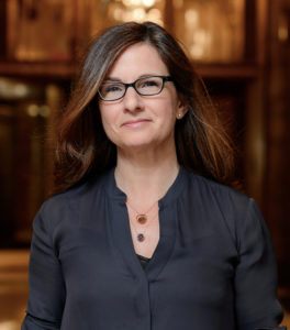 Woman with brown hair and black glasses smiling