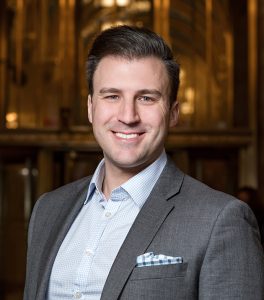 man wearing gray suit and smiling