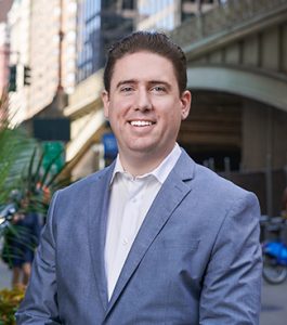 Man in blue suit smiling outside