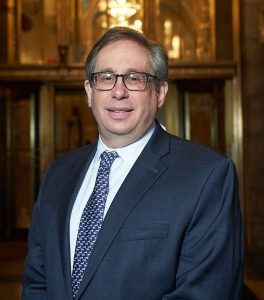 Man wearing suit and glasses and smiling