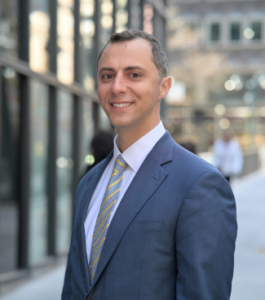 Man in blue suit standing on the street with blurred background