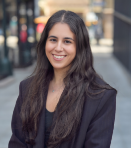 woman with suit jacket standing outside smiling